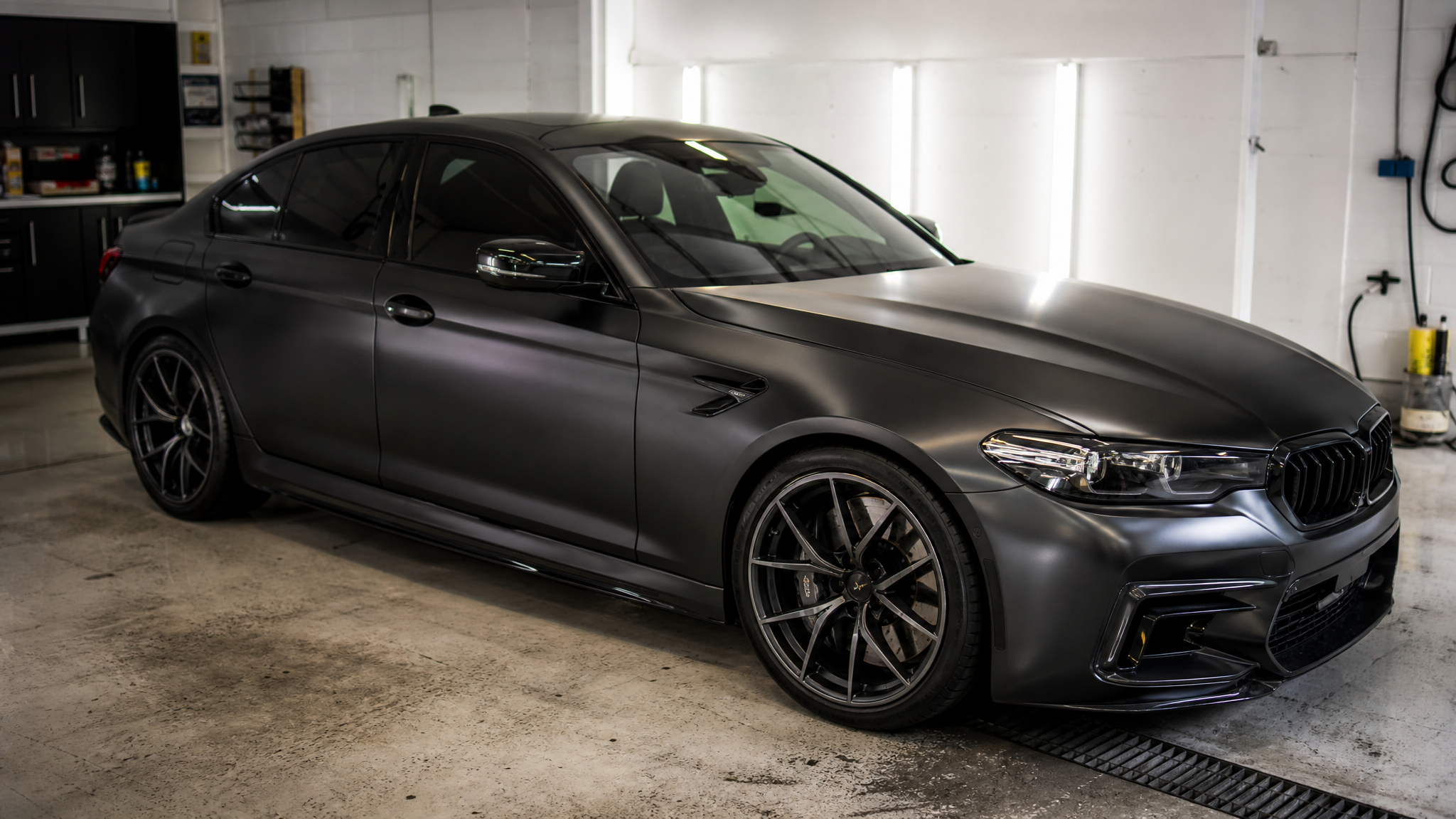 Satin black wrapped sedan in a detailing bay for black car wrap color ideas