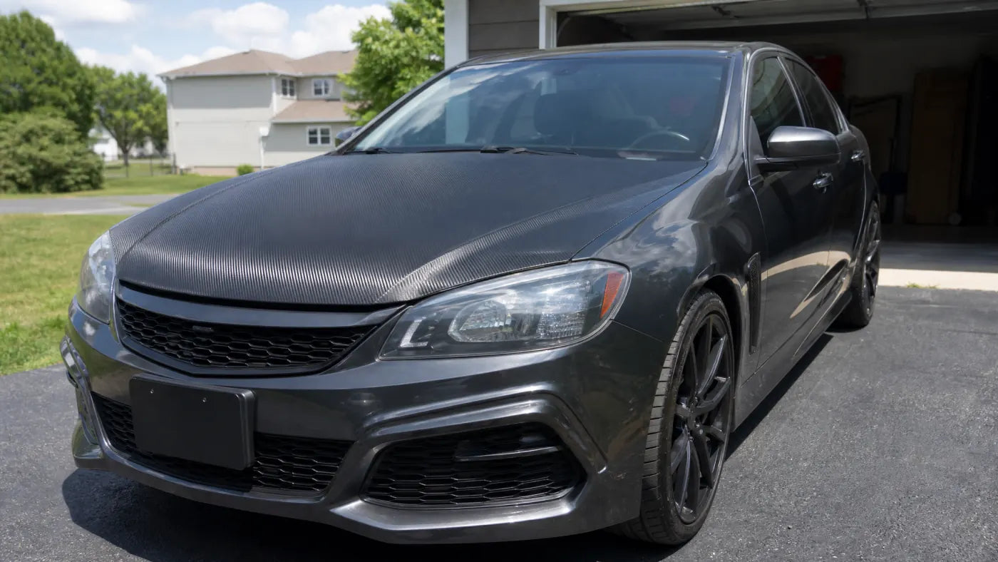 Carbon fiber vinyl hood wrap on a daily driver in driveway light