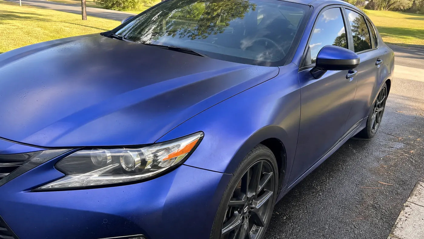 Gloss vinyl wrapped daily driver parked in natural daylight with sky and tree reflections