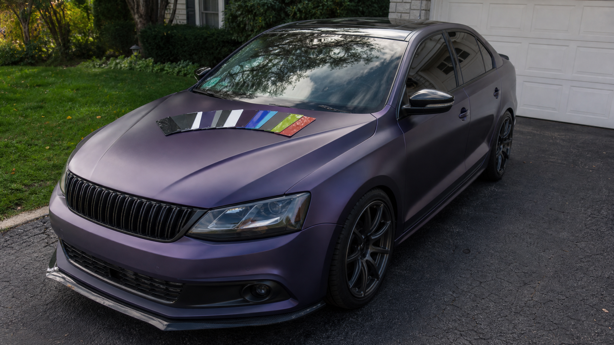 Vinyl wrap sample swatches on a car hood before choosing a full roll