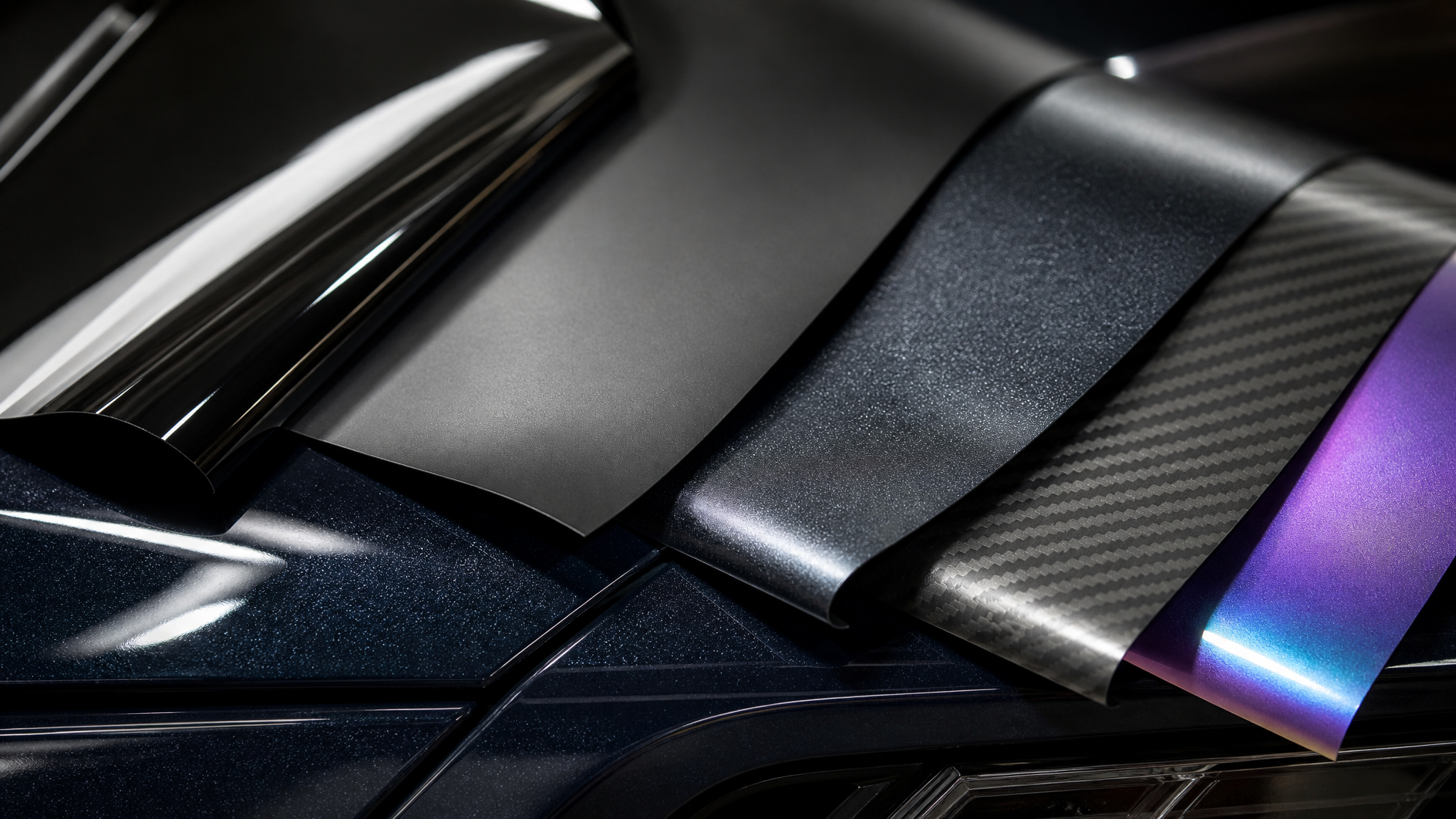 Close-up automotive wrap film surfaces showing gloss matte metallic and textured finishes